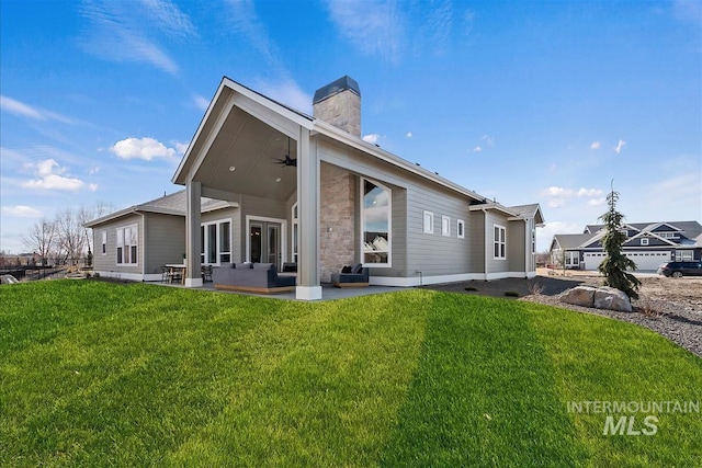 rear view of property featuring a ceiling fan, a chimney, an outdoor hangout area, a yard, and a patio area