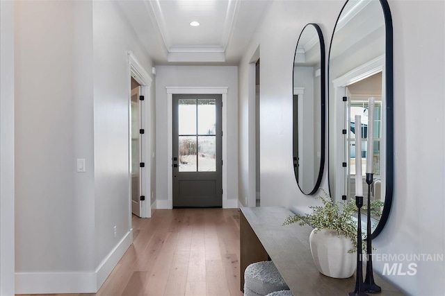 entryway with a tray ceiling, recessed lighting, ornamental molding, light wood-type flooring, and baseboards