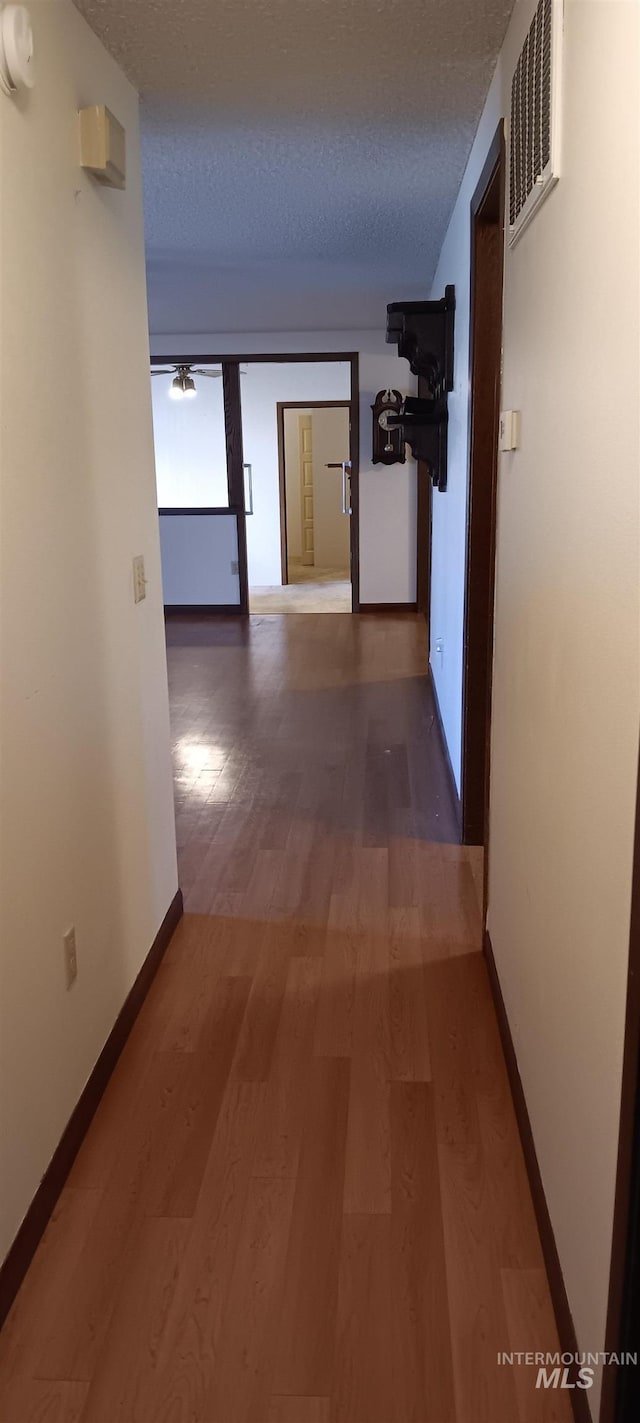 corridor featuring a textured ceiling and hardwood / wood-style floors