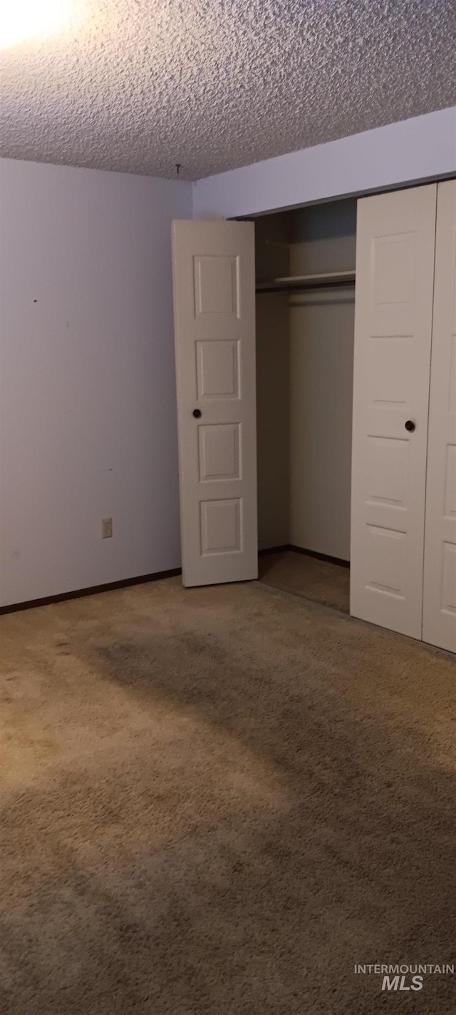 unfurnished bedroom with a textured ceiling, a closet, and carpet