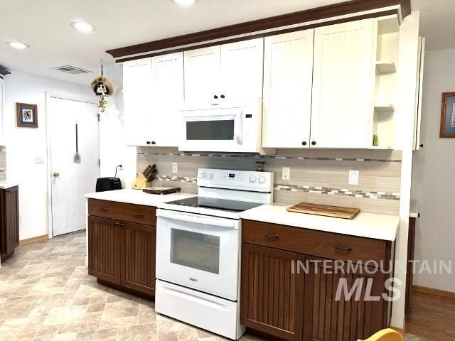 kitchen featuring dark brown cabinetry, white cabinets, white appliances, and decorative backsplash