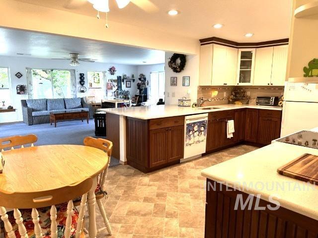 kitchen with white appliances, white cabinetry, dark brown cabinets, decorative backsplash, and kitchen peninsula