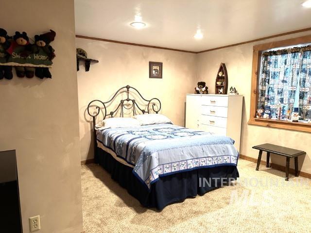 bedroom with ornamental molding and light carpet