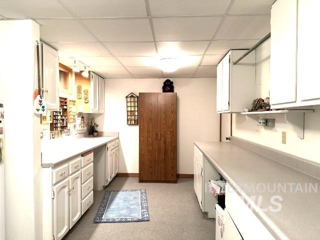 kitchen featuring white cabinetry, a paneled ceiling, and light colored carpet