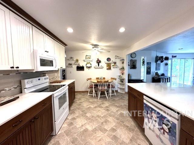 kitchen featuring dark brown cabinetry, white cabinetry, tasteful backsplash, white appliances, and beverage cooler