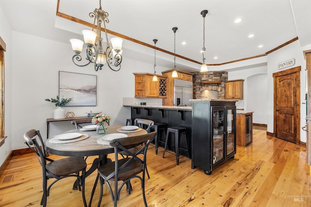 dining room featuring crown molding, a raised ceiling, light hardwood / wood-style flooring, and wine cooler