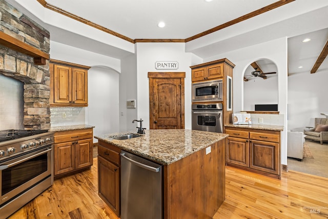 kitchen with sink, tasteful backsplash, a kitchen island with sink, stainless steel appliances, and light hardwood / wood-style floors