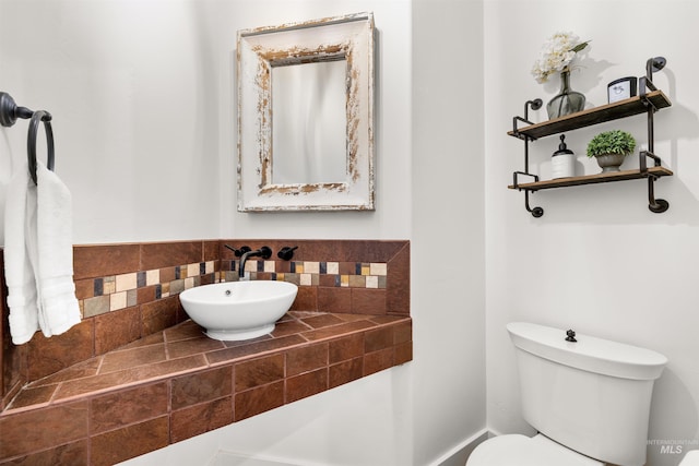 bathroom featuring toilet, sink, and decorative backsplash