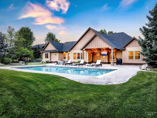 pool at dusk with a patio, a grill, and a lawn