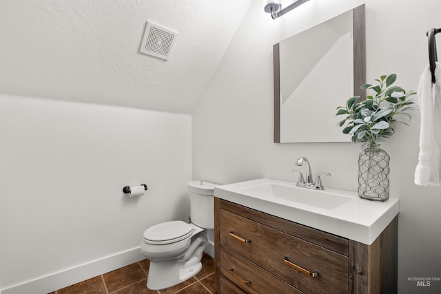 bathroom featuring vaulted ceiling, vanity, toilet, tile patterned floors, and a textured ceiling