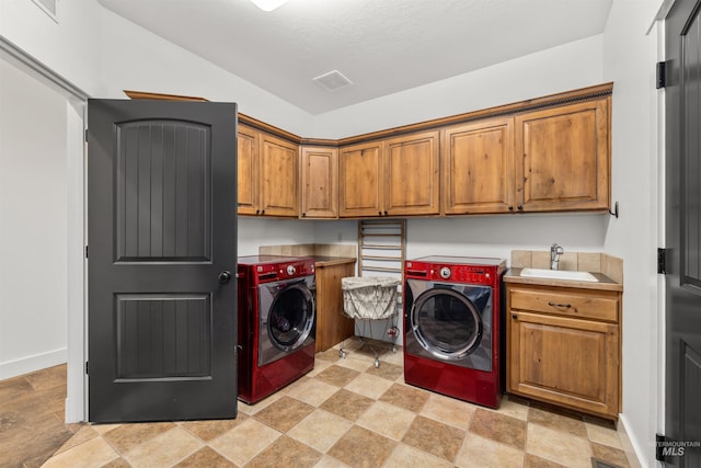 laundry room with cabinets, washer and clothes dryer, and sink