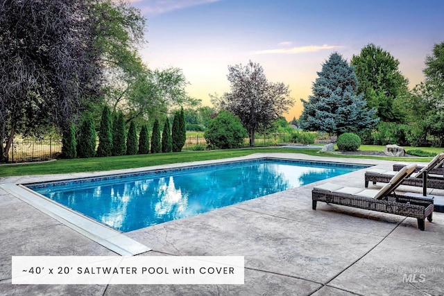 pool at dusk featuring a yard and a patio