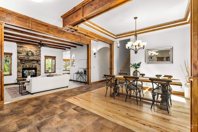 dining space with ornamental molding, dark hardwood / wood-style floors, ceiling fan with notable chandelier, and a fireplace