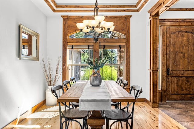 dining space featuring crown molding, light wood-type flooring, a chandelier, and a tray ceiling