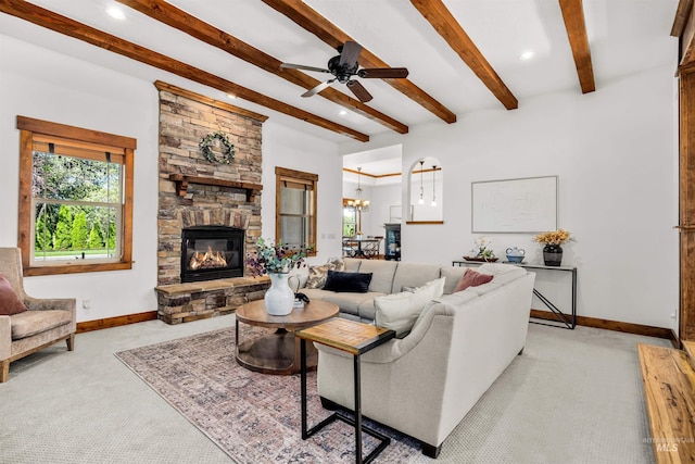 carpeted living room featuring ceiling fan with notable chandelier, a fireplace, and beam ceiling