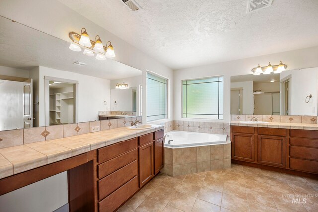 bathroom featuring a shower stall, a garden tub, tile patterned floors, vanity, and a textured ceiling