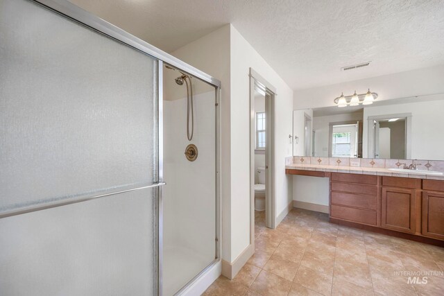 bathroom with a stall shower, toilet, double vanity, tile patterned flooring, and baseboards