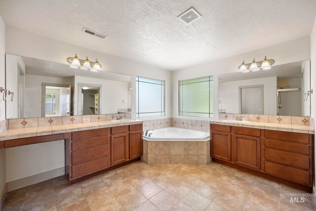 bathroom with a bath, two vanities, a shower stall, a textured ceiling, and tile patterned flooring