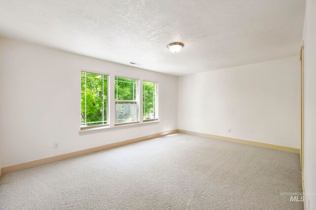 carpeted empty room featuring baseboards and a textured ceiling