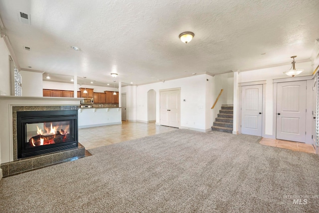 unfurnished living room featuring recessed lighting, baseboards, stairway, light colored carpet, and a textured ceiling