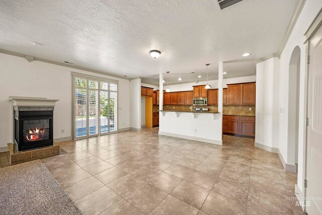 unfurnished living room with a high end fireplace, baseboards, recessed lighting, a textured ceiling, and ornamental molding