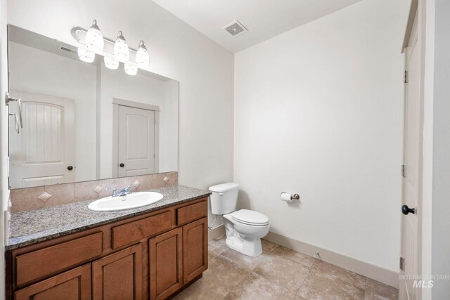 bathroom with baseboards, toilet, and vanity