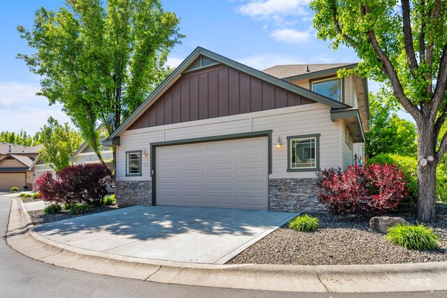 view of front facade featuring stone siding, an attached garage, driveway, and board and batten siding