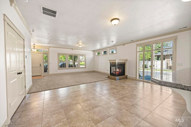 unfurnished living room with a multi sided fireplace, healthy amount of natural light, baseboards, a textured ceiling, and light tile patterned flooring