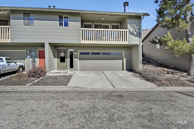 multi unit property featuring a balcony, concrete driveway, and a garage