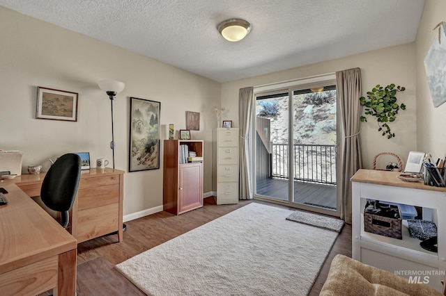 home office featuring wood finished floors, baseboards, and a textured ceiling