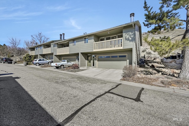 view of front facade featuring concrete driveway, a balcony, and an attached garage