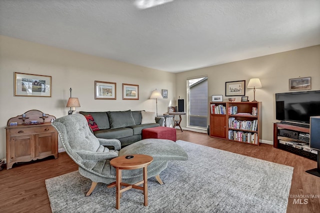 living area with a textured ceiling, baseboards, and wood finished floors