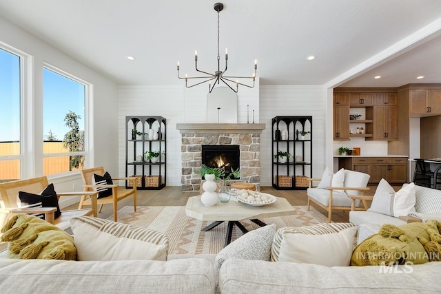 living room with an inviting chandelier, a fireplace, and light wood-type flooring