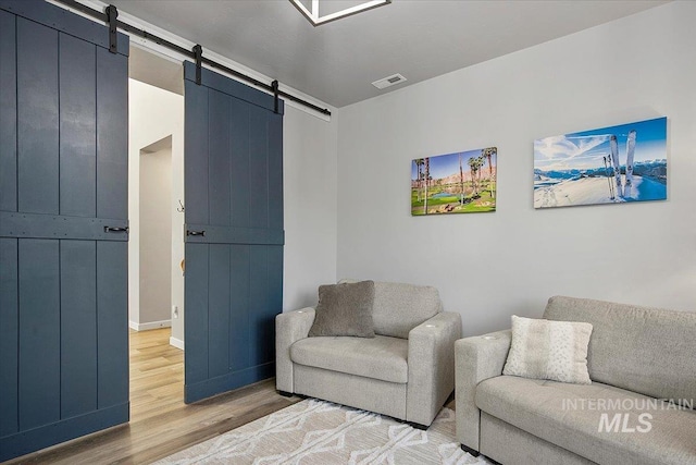 living area with a barn door and wood-type flooring