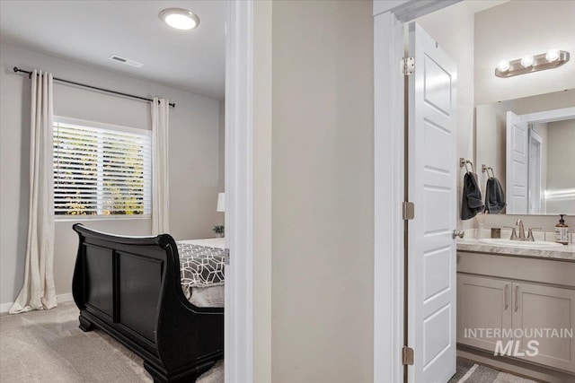 bedroom with sink and light colored carpet