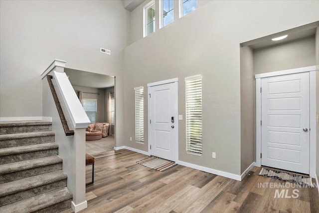 foyer entrance featuring a high ceiling, a wealth of natural light, and light hardwood / wood-style flooring