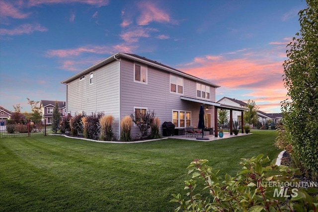 back house at dusk featuring a patio area and a yard