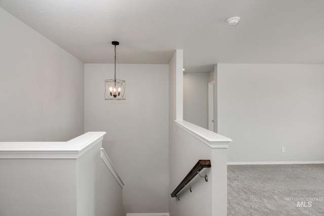 stairs with a chandelier and carpet flooring