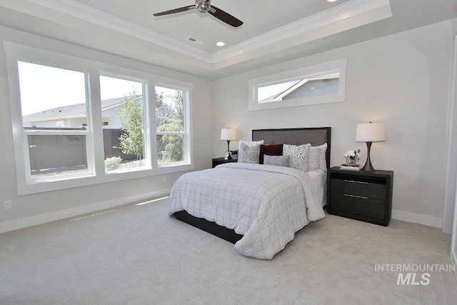 carpeted bedroom featuring ceiling fan, ornamental molding, and a raised ceiling