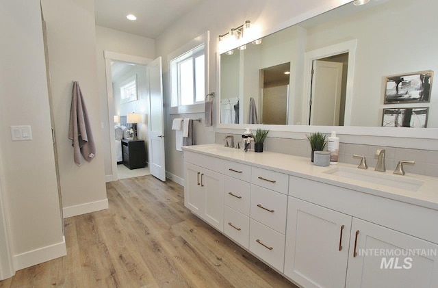 bathroom with wood-type flooring, decorative backsplash, and vanity