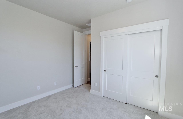 unfurnished bedroom featuring a closet and light carpet