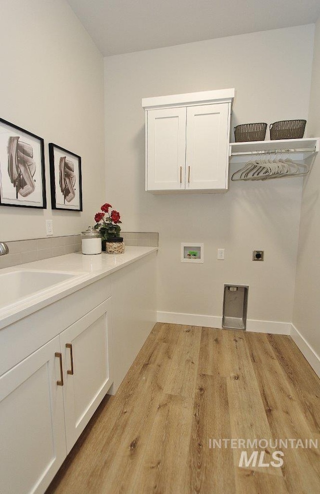 clothes washing area with sink, light wood-type flooring, hookup for a washing machine, hookup for an electric dryer, and cabinets