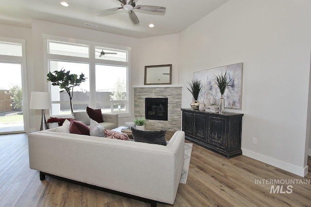 living room with a tiled fireplace, hardwood / wood-style flooring, and ceiling fan