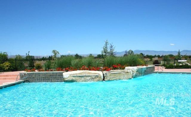 view of pool with a mountain view and pool water feature