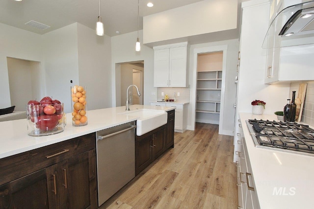 kitchen featuring hanging light fixtures, sink, white cabinetry, decorative backsplash, and stainless steel appliances