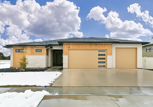 prairie-style house with a garage, driveway, and a shingled roof