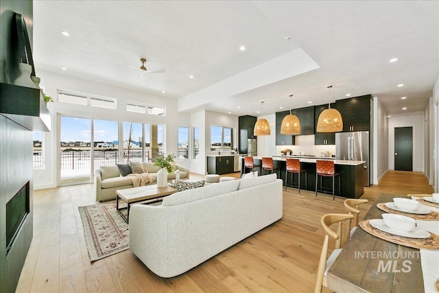 living room with light wood-type flooring, a ceiling fan, and recessed lighting