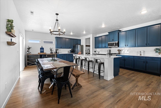 dining space featuring visible vents, baseboards, wood finished floors, a notable chandelier, and a textured ceiling