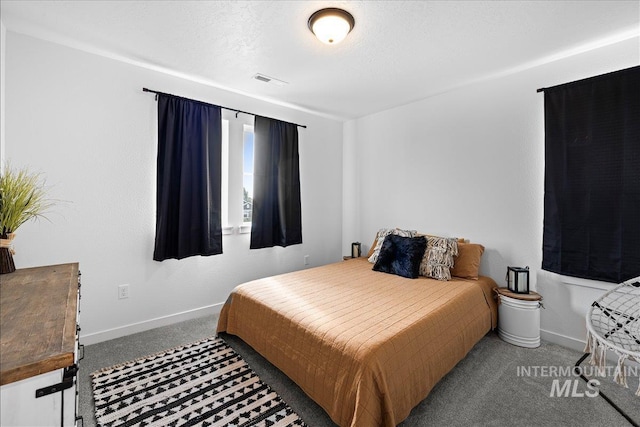 carpeted bedroom with visible vents, baseboards, and a textured ceiling