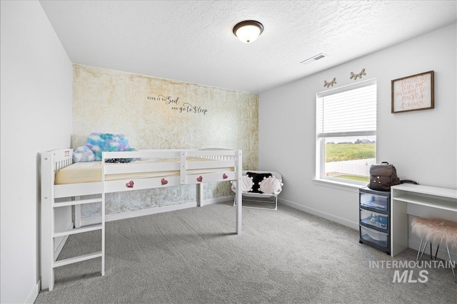 carpeted bedroom with visible vents, a textured ceiling, and baseboards